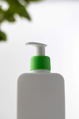 A minimalist white bottle with a green pump on a soft white background, natural beauty care. Skin care