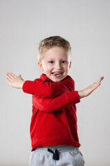 A little boy standing upright with his hands in the air