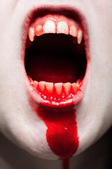 Close up mouth of scary gothic girl with white bloody teeth screaming.