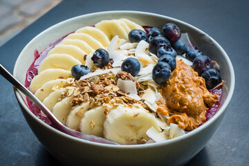Smoothie bowl with  acai powder,  blueberries, peanut butter, banana, roasted coconut flakes and...