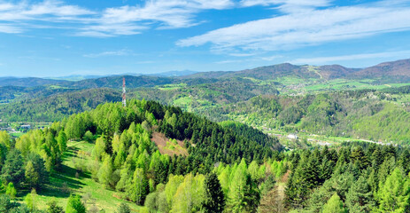 Mountains scenery in springtime. Panorama of grassland and forest in Beskid Sadecki mountains. View from Malnik top above Muszyna spa, Poland.