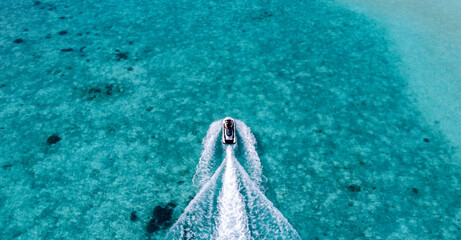 A jet ski moving leaving a wake behind in the crystal clear ocean water of the Maldives, Indian...