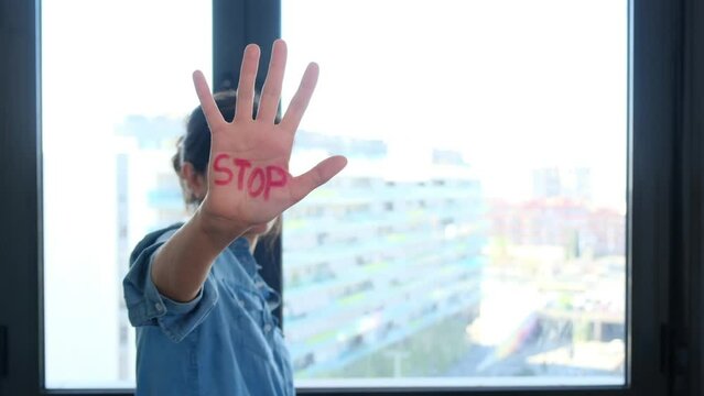 Woman with palm of hand written the word stop. Equal rights, no gender discrimination. Effective equality of rights and equity between gender and women.
