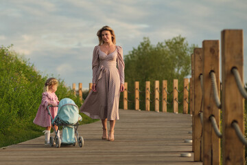 Strolling on a wooden bridge, a mother and daughter enjoy an evening walk. The scene echoes everyday family leisure.