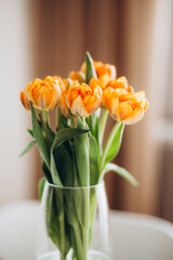 Orange tulips in a vase on the table.