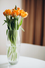 Orange tulips in a vase on the table.