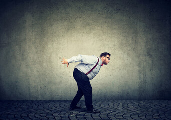 Business man bending over under imaginary burden and difficulties 