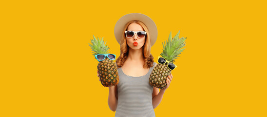 Summer portrait of happy young woman with pineapple fruit on yellow studio background