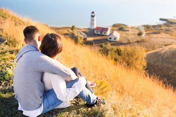 Romantic couple dressed in cozy sweaters together near the lighthouse