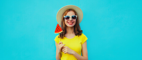 Summer portrait of happy young woman with lollipop watermelon wearing straw hat on blue background