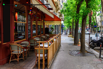 Fototapeta na wymiar Cozy street with tables of cafe in quarter Montmartre in Paris, France. Cityscape of Paris. Architecture and landmarks of Paris