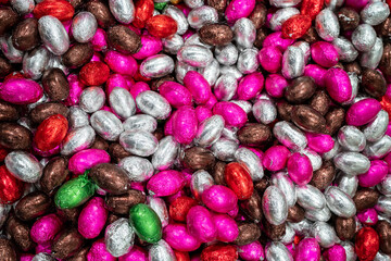 A lot of candies for background. Colorful chocolate easter eggs. Pile or group of multi colored...