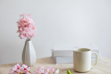 Obraz na płótnie Canvas テーブルに置かれた桜の花瓶とマグカップと本