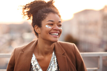 Outdoor portrait of happy glamour african american woman with glitter on face