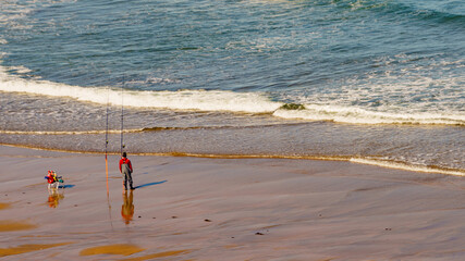 Angler with fishing rod on sea shore - 784517834