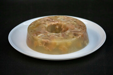 Traditional Ukrainian festive cold appetizer. Pork jelly with pieces of meat with parsley isolated on a white background. Drehlhi