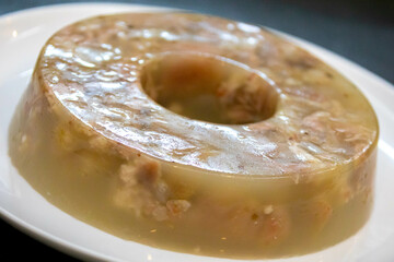 Traditional Ukrainian festive cold appetizer. Pork jelly with pieces of meat with parsley isolated...