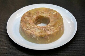 Traditional Ukrainian festive cold appetizer. Pork jelly with pieces of meat with parsley isolated on a white background. Drehlhi