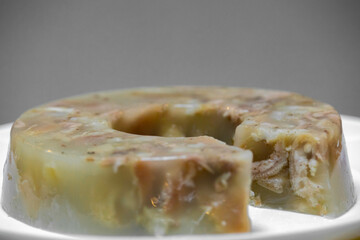 Traditional Ukrainian festive cold appetizer. Pork jelly with pieces of meat with parsley isolated on a white background. Drehlhi