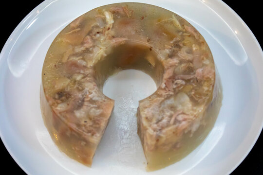 Traditional Ukrainian festive cold appetizer. Pork jelly with pieces of meat with parsley isolated on a white background. Drehlhi