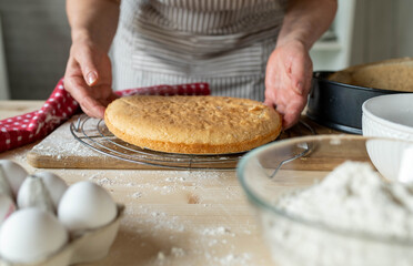 Placing a fresh baked cake base on a cooling rack by woman´s hands