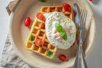Tasty and waffles with with cherry tomatoes and fried eggs.