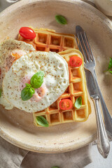 Delicious waffles with with fried eggs, tomatoes and basil.