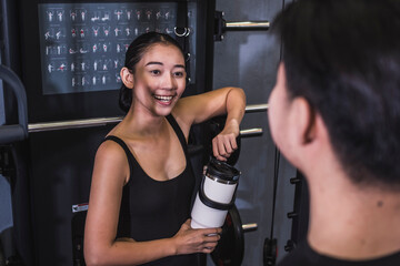 A young Asian woman converses with a man at the gym, striking a friendly chord with smiles and a casual vibe, suggesting a budding romantic interest.
