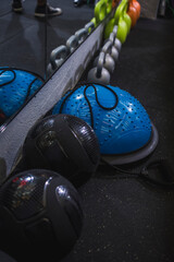 Medicine and Bosu Balls and kettlebells on the floor of a gym.