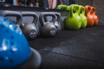 A neat row of colorful kettlebells in different sizes on a gym floor, perfect for strength training and fitness routines.