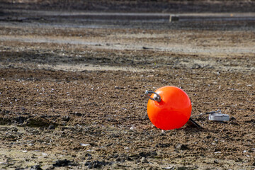 Red buoy on the ground of a dried out lake