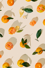 Fresh tangerines on beige background with sunlight shadows, minimal aesthetic citrus fruits as summer food pattern, healthy organic orange colored mandarin with green leaves top view, trend still life