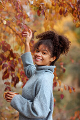 Young happy smiling mixed-race woman with coffee cup in autumn nature, pleased african american...