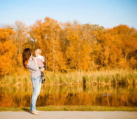 Fototapeta premium Smiling mother and baby on autumn lake