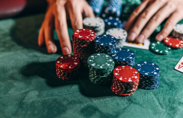 A man's hands hold a stack of poker chips at a casino table, depicting a poker game concept