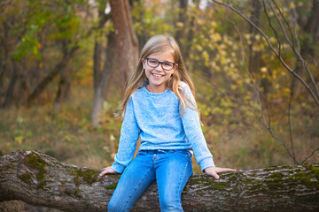 Portrait of a blonde girl with glasses outdoors in the park on the autumn park background