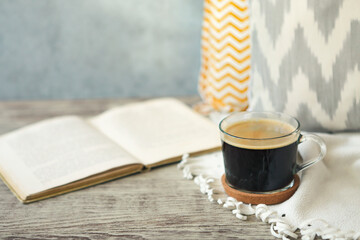 Cup of coffee staying by the book on the wooden table