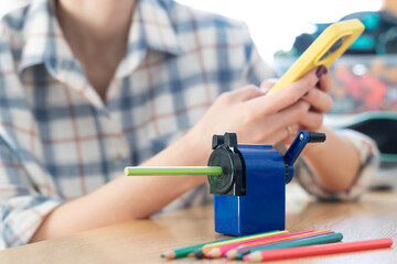 Close-up shot of a girl sharpening pencils using a special creative sharpener	