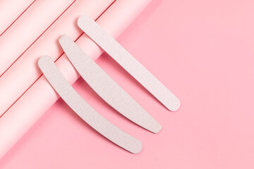 Set of gray nail files of different shapes and different stiffness. Tools for manicure on pastel pink background. Isometric, modern photo.