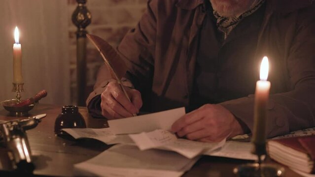 18th century man signs a letter using a quill pen