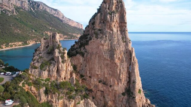 Aerial drone view of cliffs of Punrta Pedra Longa on Sardegna. Warm turquoise sea, height rocks and beach with green mountains on the Sardinia island.