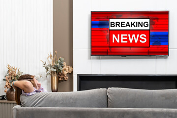 Back view on excited man sitting on the couch and watching breaking news on tv at home	