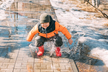 Gleeful Puddles : With every step, the child's red boots send a cascade of droplets into the air, a...