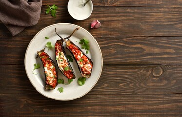 Roasted aubergine with yogurt and tomato sauce dressing over wooden background with free space
