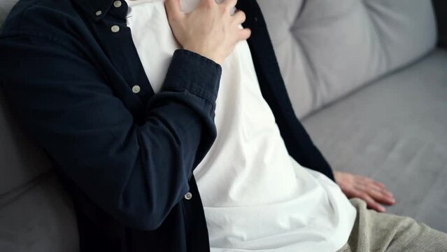 A person is suffering from heart problems, holds his chest with his hand and waits for help, the pain constrains his movements,
heart colitis