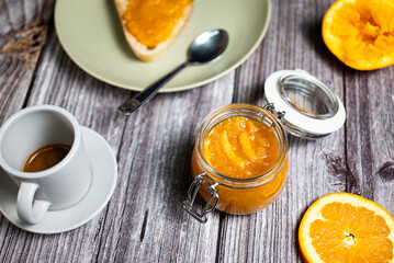 Healthy breakfast with homemade orange marmalade. Glass jar with homemade orange jam, slice of bread with jam