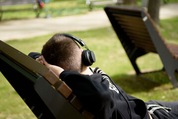 A young guy in earphones listens to music in nature. Poland, Zielona Gora