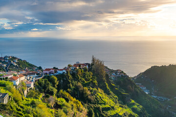 Fototapeta na wymiar Taditional Madeiran houses in Funchal behind a banana plantation and ocean sunset.