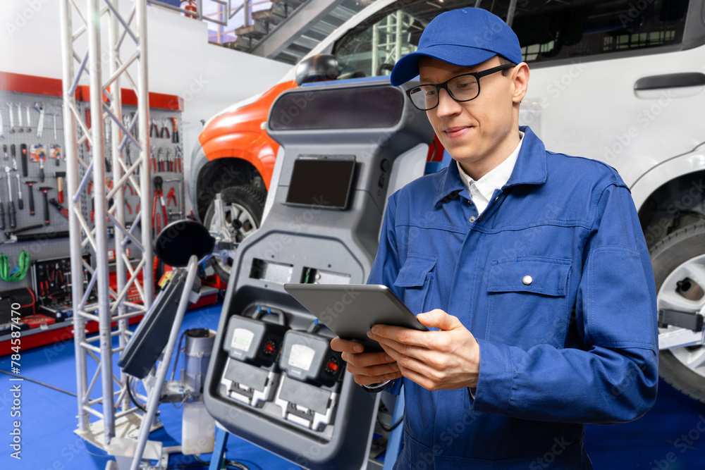 Poster serviceman with digital tablet on the background of the car in the car service.