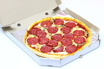 Freshly baked pizza with sausage in a cardboard box on a white background
